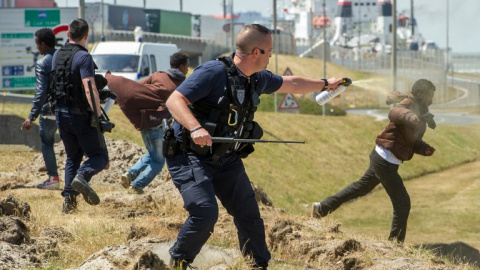 Fotografía de junio de 2015 de un policía gaseando a un inmigrante en Calais. - AFP