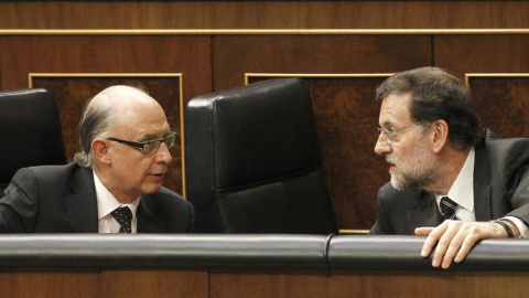 El presidente del Gobierno, Mariano Rajoy, conversa con el ministro de Hacienda, Cristóbal Montoro, en sus escaños de la bancada azul del Congreso de los Diputados. EFE