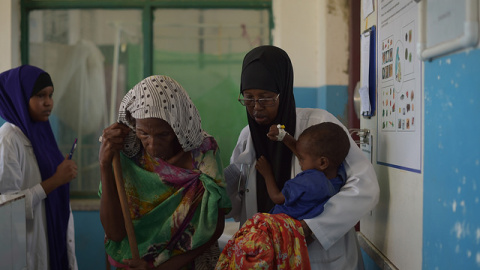 Una enfermera del hospital de Banadir en Mogadiscio, Somalia, ayudó a una anciana, que llevó a su nieto desnutrido al hospital a recibir tratamiento para la desnutrición. AMISOM Photo / Tobin Jones