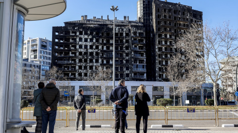 Varias personas observan el edificio incendiado del barrio de Campanar, a 24 de febrero de 2024, en Valencia