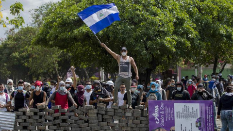 Un joven levanta una bandera de Nicaragua sobre una barricada de adoquines hoy, sábado 21 de abril de 2018, durante el cuarto día de protestas en Managua (Nicaragua). La agitación social se mantuvo hoy por cuarto día en Nicaragua pese a que el preside