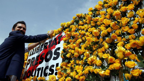 El presidente del Parlament, Roger Torrent, coloca una rosa amarilla en el panel que Omnium Cultural ha instalado en la plaza de Cataluña para pedir la libertad de los políticos independentistas presos. EFE