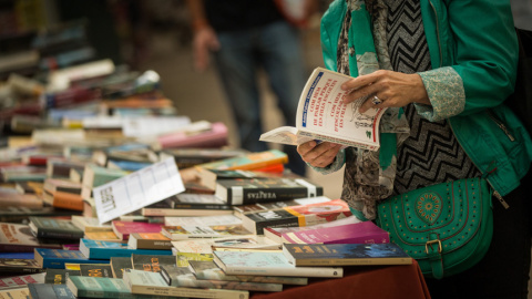 Una mujer hojea un libro en una de las paradas de las Ramblas de Barcelona durante la diada de Sant Jordi