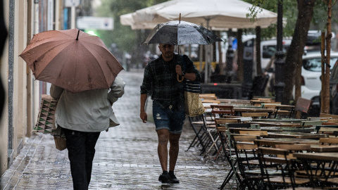 Varias personas se resguardan de la lluvia con paraguas, a 3 de septiembre de 2023, en Madrid