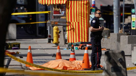 Un policía permanece de pie al lado de una de las víctimas del atropello. | (REUTERS)