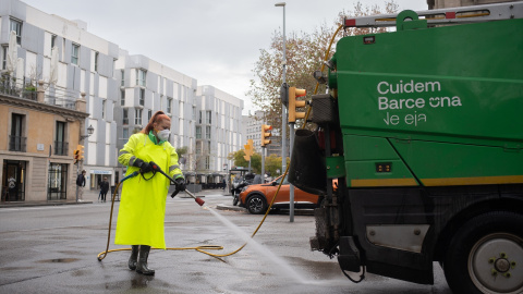 Una trabajadora de la limpieza riega una calle con una manguera en Barcelona, Catalunya.