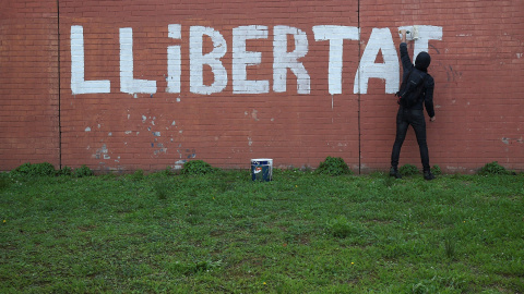 Un hombre pinta en un muro la palabra "LLIBERTAD" en Barcelona.REUTERS/Albert Gea