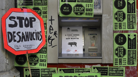 Un cajero automático en Barcelona cubierto por carteles de la plataforma antidesahucios. AFP/Lluis Gene