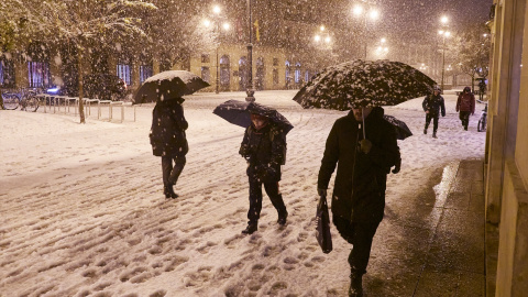 Varias personas caminan por una calle nevada, a 19 de enero de 2023, en Pamplona, Navarra.