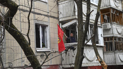 Un hombre ondeando una bandera roja desde el balcón de un edificio dañado tras un bombardeo en el centro de Belgorod, Rusia, el 16 de marzo de 2024.