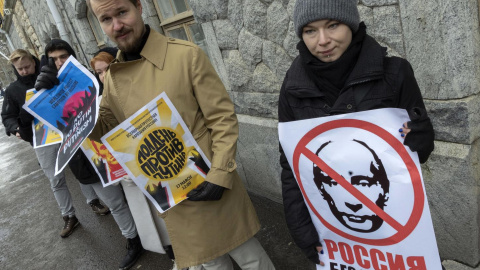 Manifestantes sostienen pancartas con una imagen tachada de Vladimir Putin, mientras los rusos que viven en Finlandia se reúnen para votar en la embajada rusa en Helsinki. 17-03-2024