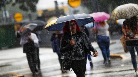 Una mujer cruza un paso de peatones durante una fuerte tormenta, en el centro de Buenos Aires (Argentina). EFE/David Fernández