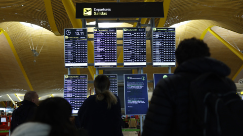 Varias personas comprueban los paneles de información tras el fallo de conectividad en los sistemas de Iberia.