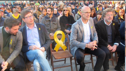 Gabriel Rufián, Carles Mundó, Raül Romeva i Antoni Castellà, en un acte a Vilanova i la Geltrú, deixen una cadira buida amb el llaç grog, per assenyalar l'obligada absència d'Oriol Junqueras / Europa Press