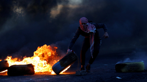 Un palestino sujeta un neumático en llamas durante las protestas producidas tras el reconocimiento de Jerusalén como capital de Israel por parte de Trump./REUTERS