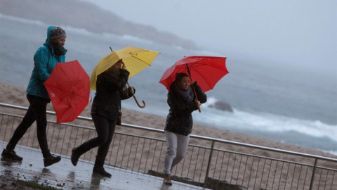 Tres mujeres se protegen de la lluvia en el paseo marítimo de A Coruña. - EFE