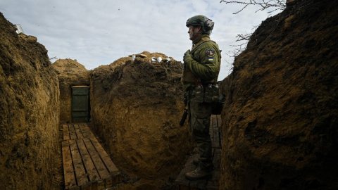 Un soldado ucraniano observando tras una trinchera.