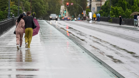 Dos personas caminan con dificultad por Sevilla debido al viento y la lluvia, a 19 de octubre de 2023.