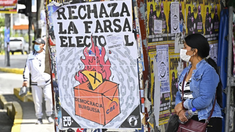 Una mujer camina junto a carteles que piden el voto negativo en el referéndum.