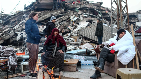 Varias personas intentan calentarse con fuego en las calles de Hatay (Turquía) después de quedarse sin casas, destruidas por el terremoto, este 8 de febrero de 2023.