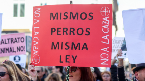 Una mujer porta una pancarta con el lema 'Mismos perros, misma ley' durante una manifestación contra la caza en Madrid.