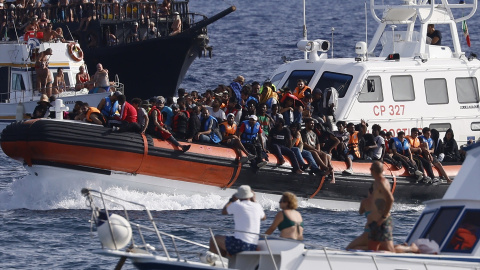 Migrantes rescatados llegan en un barco al puerto de Lampedusa entre dos barcos de turistas, a 18 de septiembre de 2023.