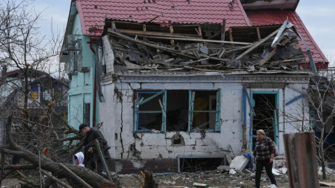 Varios vecinos caminan entre los escombros de una casa tras un ataque ruso en Ucrania.