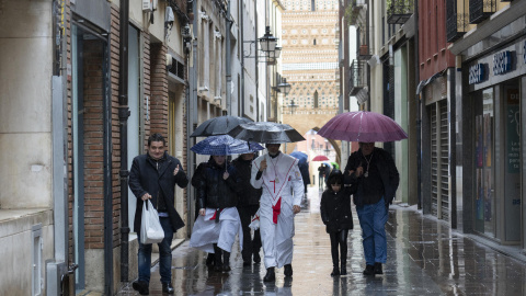 Varias personas caminando bajo la lluvia en Teruel, a 31 de marzo de 2024