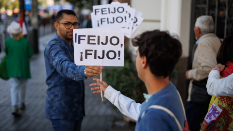 Dos personas sujetan pancartas que aluden al líder del PP, Alberto Núñez Feijóo, a 24 de septiembre de 2023, en Madrid.