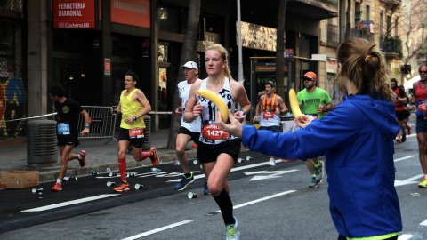 17-3-2023 Una voluntària ofereix un plàtan a una participant mentre corre a la Marató de Barcelona