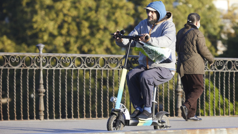 Una persona en su patinete, en Puente de Triana, en Sevilla.