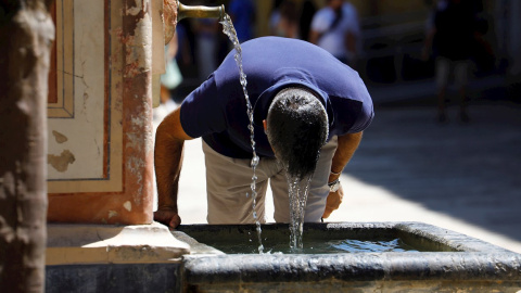 Un visitante se refresca en una fuente del Patio de los Naranjos de la Mezquita Catedral de Córdoba este sábado, en una jornada de intenso calor en la ciudad andaluza.