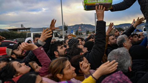 Supervivientes del terremoto en Turquía tratan de alcanzar suministros el 7 de febrero de 2023, en la provincia de Hatay.