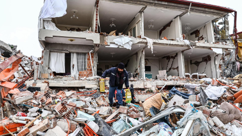 Un hombre carga con botellas de aceite y pasa por los escombros de una casa destrozada por el terremoto en la ciudad turca de Kahramanmaras este 7 de febrero de 2023.