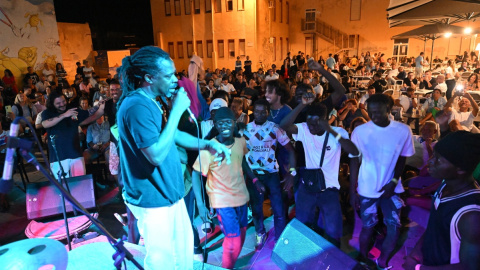 Migrantes recién desembarcados, vecinos y turistas cantan y bailan en una plaza de Lampedusa (Italia), donde han llegado 10.000 migrantes en apenas tres días.