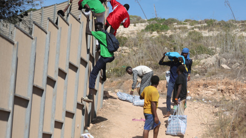 Varias personas migrantes escapan del 'hotspot' de Lampedusa, Italia, colapsado tras la llegada de más de 10.000 personas en tres días.