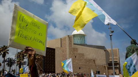 Una persona sujeta un cartel de protesta durante una manifestación contra el modelo turístico, a 20 de abril de 2024, en Las Palmas de Gran Canaria, Gran Canaria, Canarias (España).