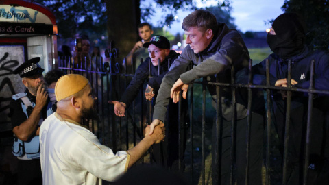 Un miembro de la mezquita Abdullah Quilliam estrecha la mano de un manifestante durante una manifestación en la mezquita Abdullah Quilliam en Liverpool, Gran Bretaña, el 02 de agosto de 2024.