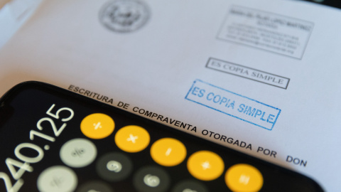 Una calculadora y una escritura de compraventa de una hipoteca, a 2 de junio de 2022, en Madrid.