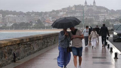 Dos personas se protegen de la lluvia con un paraguas en la playa de Ondarreta, a 14 de octubre de 2023, en San Sebastián