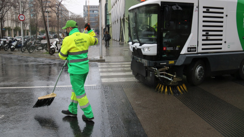 Un treballador netejant a la superilla del Poblenou de Barcelona, juntament amb una de les màquines de la nova flota de vehicles.