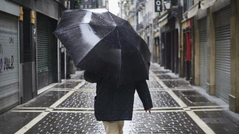 Un hombre camina protegiéndose con un paraguas por la lluvia por el casco viejo de Pamplona durante el Martes Santo a 7 de abril de 2020