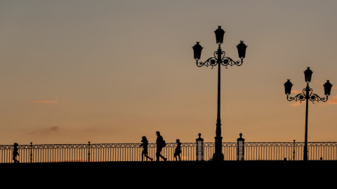 Un padre con sus hijos pasando al atardecer por el Puente de Triana, a 28 de abril del 2020, en Sevilla, Andalucía.