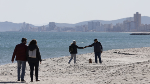 Varias personas disfrutan de las agradables temperaturas registradas este viernes, en la playa de Saler de València.