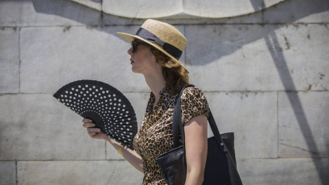 Una mujer se abanica mientras camina por la Avenida de la Constitución, en Sevilla.