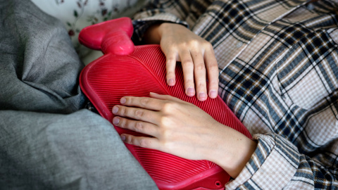 Una mujer sostiene una bolsa de agua sobre su abdomen.