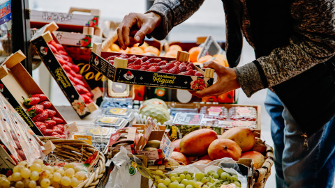 Una persona coge una caja de fresas en la frutería 'Vitaminas', a 2 de enero de 2023, en Madrid (España).