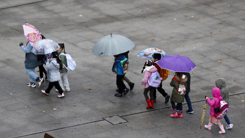 Varios niños se dirigen al colegio con botas y paraguas debido a la lluvia, en Bilbao, a 21/11/2023