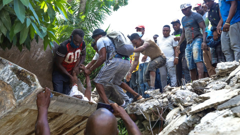 Un grupo de personas sacan un cuerpo de los escombros de un edificio tras el terremoto que ha sacudido de nuevo Haití.