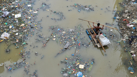 buscando productos de plástico reciclado en el canal lleno de desechos plásticos